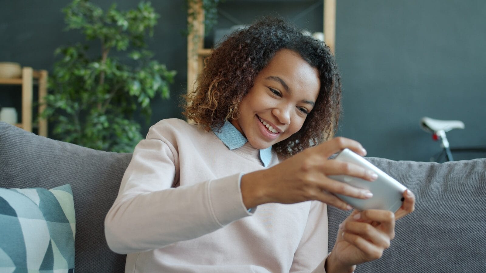 Young woman smiling while playing on her phone